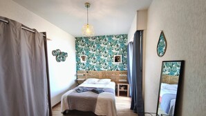 A bedroom with a bed, wooden headboard, a small bedside table, a mirror, and a wall with a tropical leaf pattern. - T2 in the heights of Ajaccio golf view sea (Ajaccio)