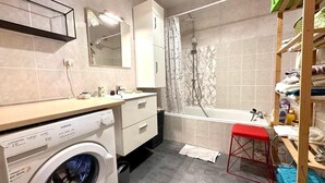 A compact bathroom with a washing machine, a bathtub, a sink, and a mirror. - T2 in the heights of Ajaccio golf view sea (Ajaccio)