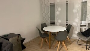 A modern dining area with a round table and four chairs, a sofa, and a glass cabinet. - Apartment in Alsdorf - near Aachen (Alsdorf)