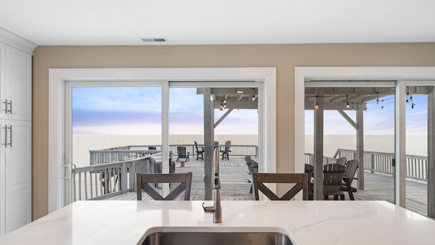 Een keuken met een groot raam met uitzicht op een terras en strand.