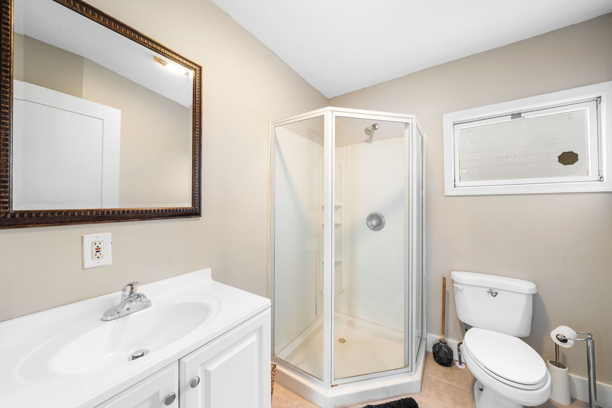 A bathroom with a glass-enclosed shower, a white sink, and a toilet.