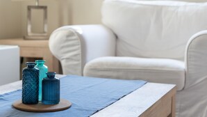 A room with a wooden table, a white armchair, and a lamp.