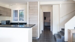 A modern kitchen with a central island, a microwave, and a window with blinds.