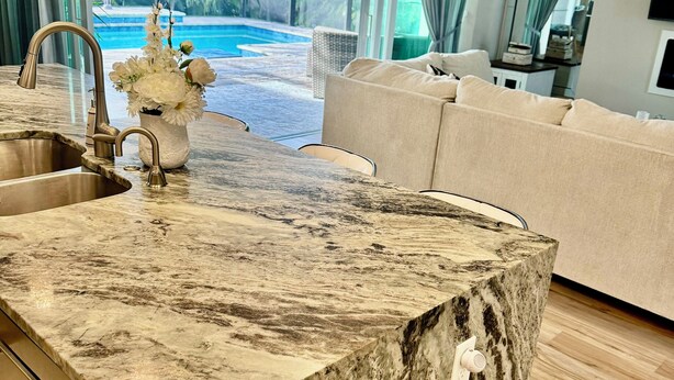 A modern kitchen with a marble countertop, a sink, and a vase of flowers. - The Ultimate Luxury 4 BR/3 BA, Heated Pool, Outdoor Kitchen (Port Charlotte)
