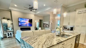 A modern kitchen with a marble countertop, white cabinets, and a built-in oven. - The Ultimate Luxury 4 BR/3 BA, Heated Pool, Outdoor Kitchen (Port Charlotte)