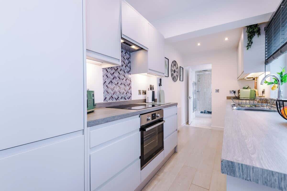 A modern kitchen with white cabinetry, a built-in oven, and a large island with a sink.