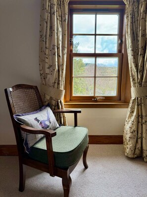 A corner room with a window, a chair, and curtains. - Traditional Scottish Cottage (Blairgowrie)