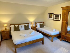 A bedroom with two wooden beds, nightstands, and a wooden wardrobe. - Traditional Scottish Cottage (Blairgowrie)