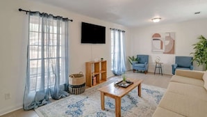A living room with a sofa, two armchairs, a coffee table, a TV, and a bookshelf. - Mins to Museum, Parks, Downtown - Parkhill Place (Mobile)