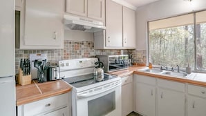 A kitchen with white cabinets, a stove, a microwave, and a window with a view of trees. - Mins to Museum, Parks, Downtown - Parkhill Place (Mobile)