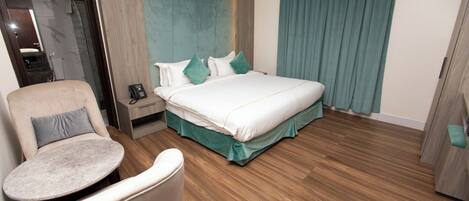 Ein Hotelzimmer mit Bett, Sessel, Nachttisch und Telefon.