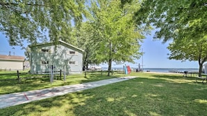 A grassy area with a small building, a path, and a view of the water. - Full Cabin: 14 Steps to the Lake!  PET FRIENDLY! (Houghton Lake)