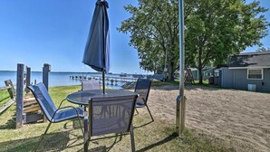 Une terrasse au bord de la plage, avec une table et des chaises, un parasol et une vue sur l’eau.