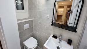 Une petite salle de bain comprenant des toilettes, un lavabo et un miroir avec un cadre noir.