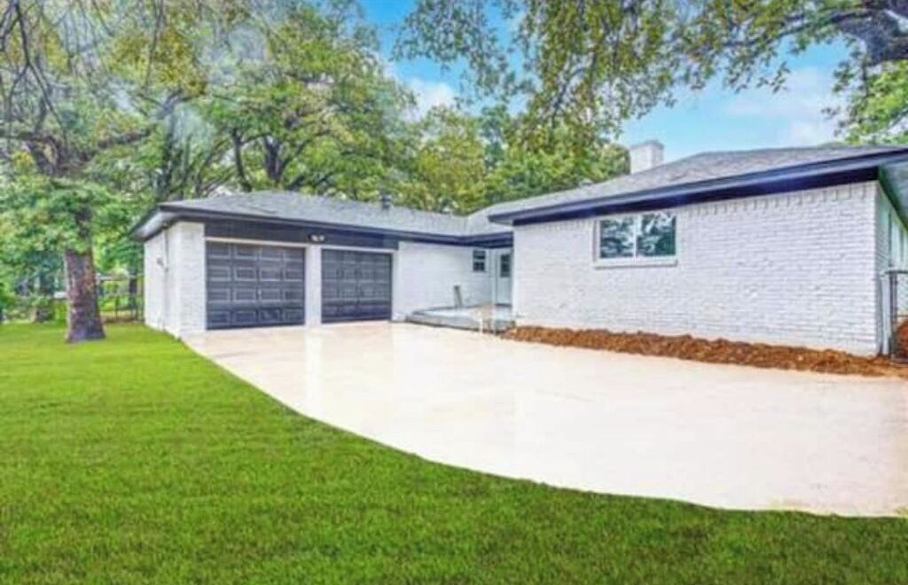A two-story house with a garage, a covered driveway, and a well-maintained lawn.