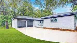 Une maison à deux étages avec un garage, une allée couverte et une pelouse bien entretenue.