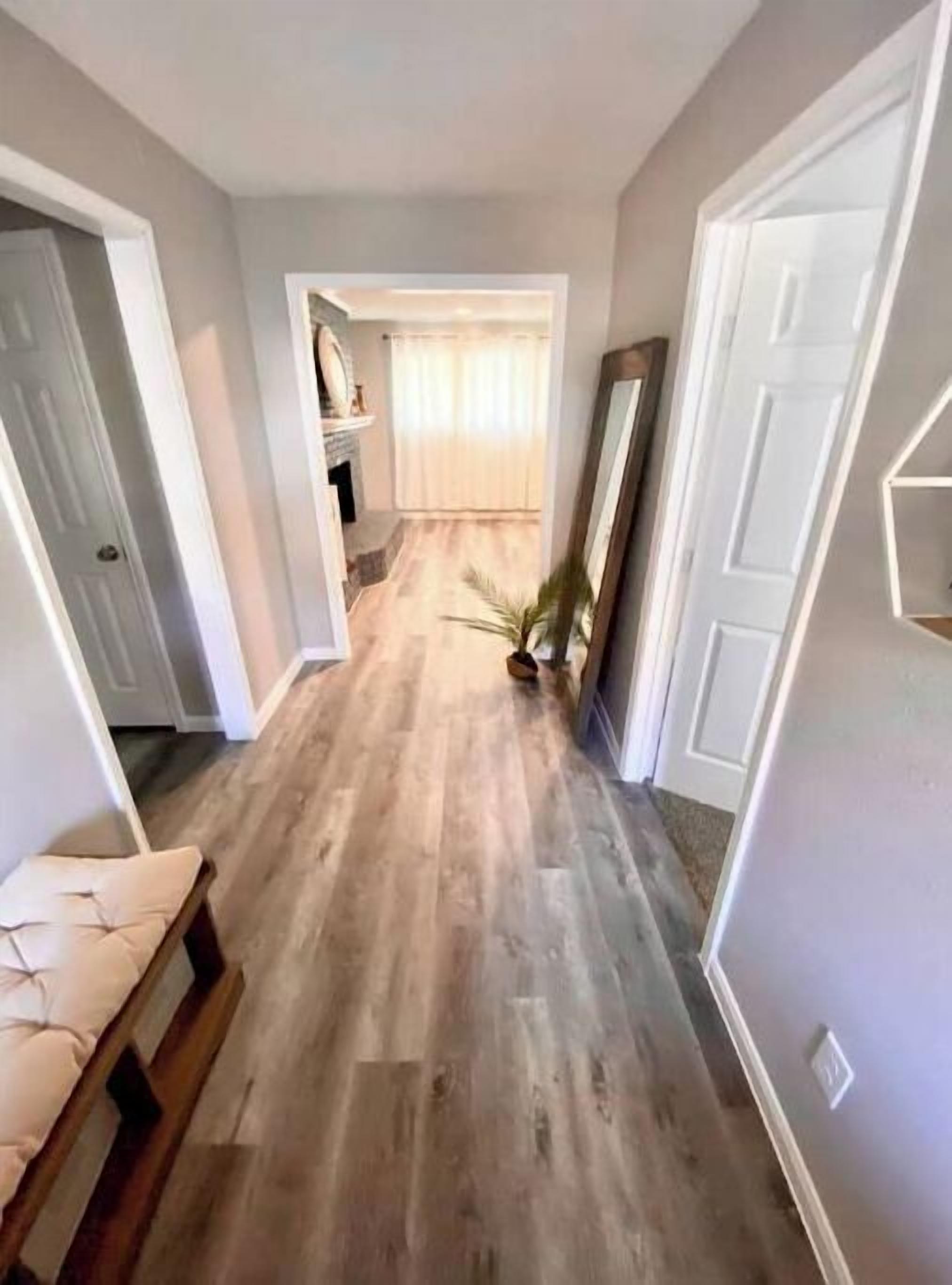 A hallway with wooden flooring, white walls, and a door on the right.