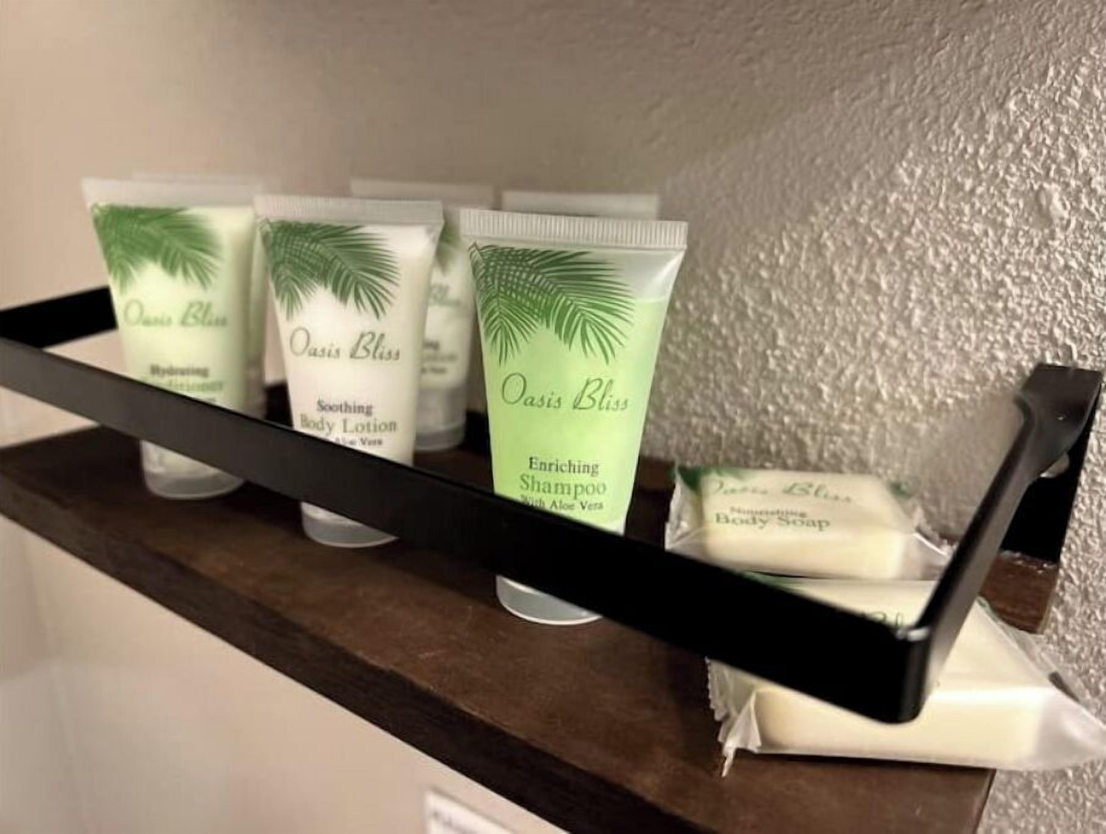 A shelf with Oasis Bliss body lotion, soothing body lotion, enriching shampoo, and body soap.
