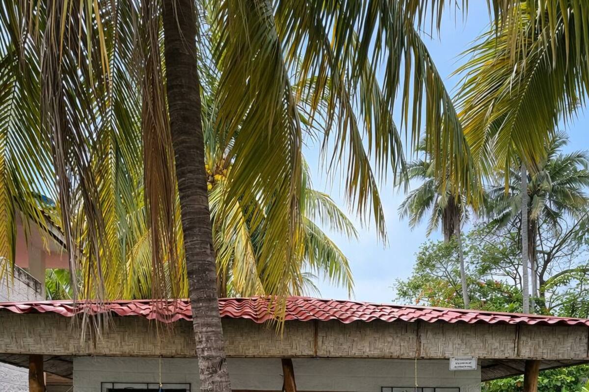 Ein Bungalow mit Ziegeldach, einer Holztür und einer kleinen Veranda mit blauem Stuhl.