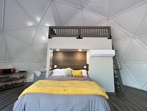 Una camera a tenda con un letto, una testiera in legno e una scala.