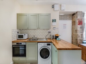 Une cuisine compacte équipée d’un four à micro-ondes, d’un four, d’un évier et d’un lave-linge.