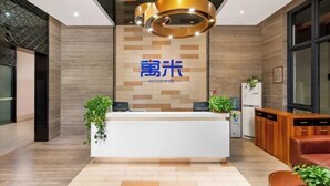 A modern reception area with a wooden reception desk, a logo above it, and a seating area with a brown sofa.