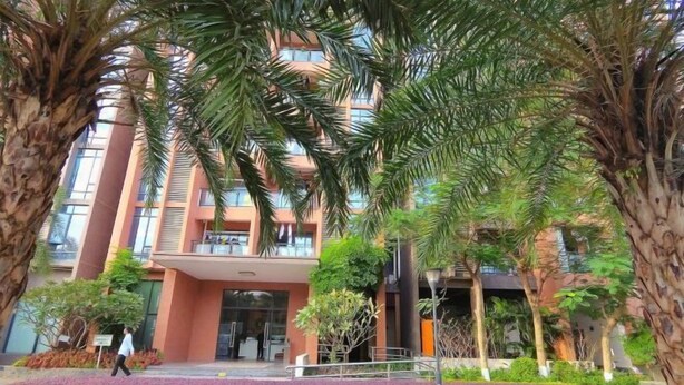 A modern building with a central entrance, surrounded by palm trees and well-maintained landscaping.