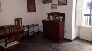 Une pièce comprenant une table à manger, des chaises, un petit bureau avec des livres et une fenêtre donnant sur un beau paysage.
