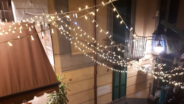 Un escalier décoré de guirlandes lumineuses, une table en bois, des chaises et une plante en pot.