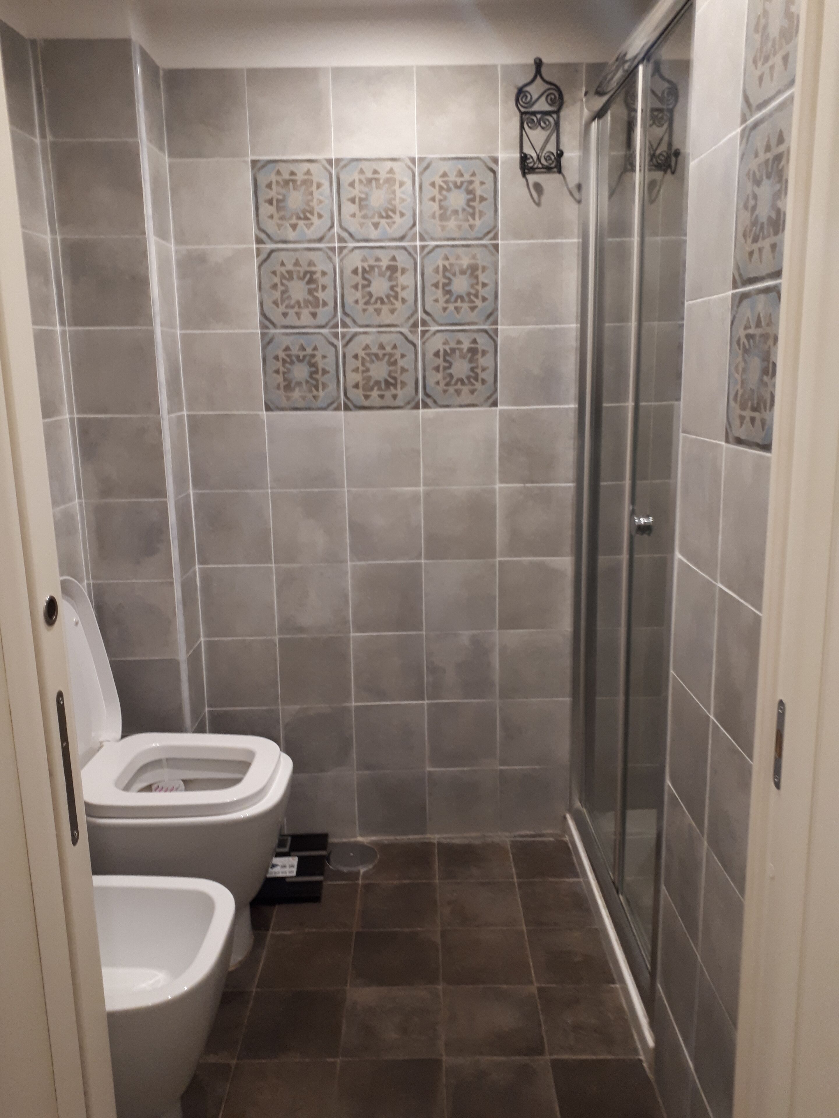 Een badkamer met een douche, toilet en een hygiëneschuimer.