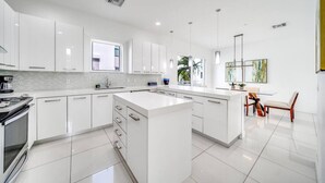 A modern kitchen with white cabinetry, a central island, and a dining area with a table and chairs.