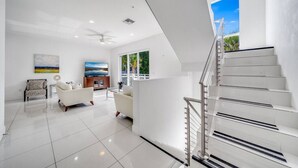 A modern living room with a white sofa, a TV, and a painting on the wall.