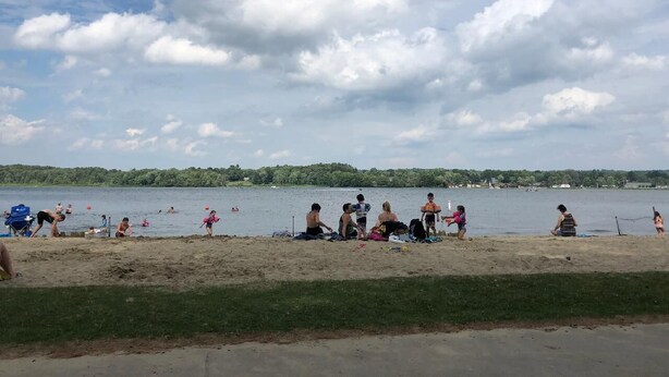 A beach with people relaxing and children playing near the water.