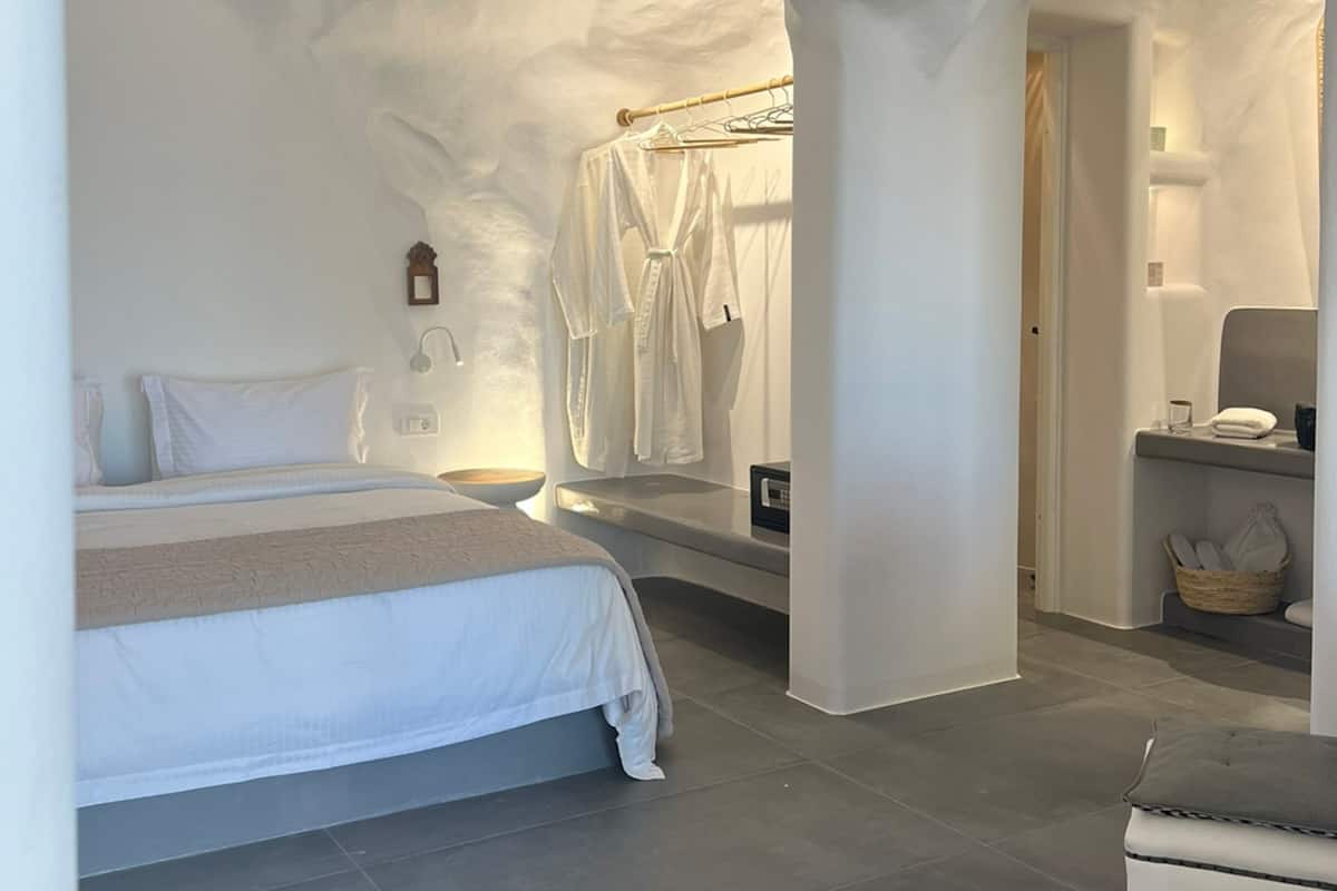 A modern bedroom with a large bed, a vanity with a mirror, and a seating area.