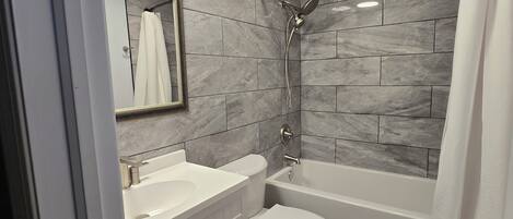 A modern bathroom with a vanity, toilet, and bathtub.