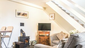 Una sala de estar acogedora con chimenea, televisor y una escalera.