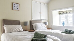 Habitación de hotel con dos camas, un armario grande, una ventana con vistas y un cuadro en la pared.