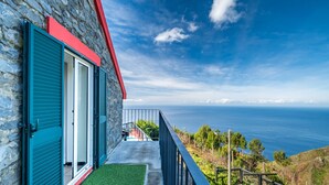 A stone building with a balcony overlooking a coastal view. - Ocean Panorama House by Madeira Sun Travel (Calheta)