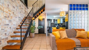 A living room with a staircase, a sofa, a coffee table, and a kitchen in the background. - Ocean Panorama House by Madeira Sun Travel (Calheta)