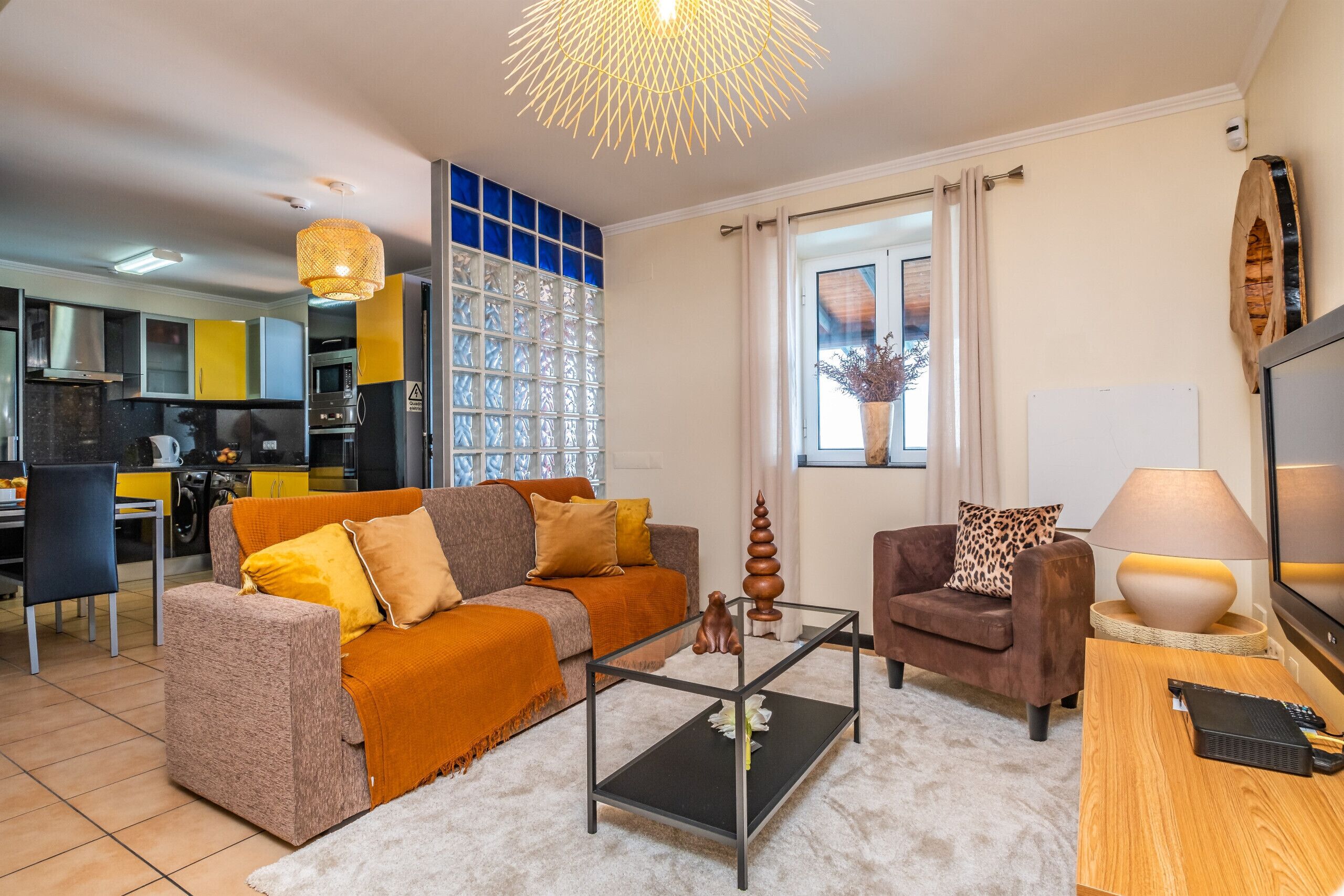 Een woonkamer met een bank, fauteuil, salontafel en een televisie.
