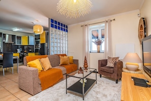 Un salon comprenant un canapé, un fauteuil, une table basse et un téléviseur.