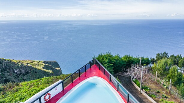 A pool with a red deck, surrounded by greenery and overlooking a vast ocean. - Ocean Panorama House by Madeira Sun Travel (Calheta)