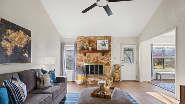 A living room with a stone fireplace, a ceiling fan, and a large abstract painting. - Lookin' and Feelin' Good in Georgetown - Long stays / Pets / Office (Georgetown)
