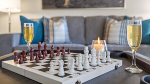 A chessboard on a table with two glasses of white wine, a lit candle, and a sofa with blue and white cushions in the background. - Lookin' and Feelin' Good in Georgetown - Long stays / Pets / Office (Georgetown)