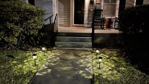A pathway leading to a house entrance with steps, a door, and a porch area with a chair and a table. - Charming and cozy home by a Historic District (Columbus)