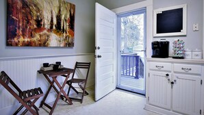 A room with a dining table, chairs, a coffee maker, and a television on a cabinet. - Charming and cozy home by a Historic District (Columbus)