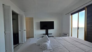 A hotel room with a large bed, a flat-screen TV mounted on the wall, and a sliding glass door leading to a balcony. - Bayfront  apartment with Breathtaking views.   1 bdr w/ balcony . Free Parking (North Bay Village)