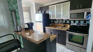 A compact kitchen with a built-in island, stainless steel appliances, and black cabinets. - Bayfront  apartment with Breathtaking views.   1 bdr w/ balcony . Free Parking (North Bay Village)