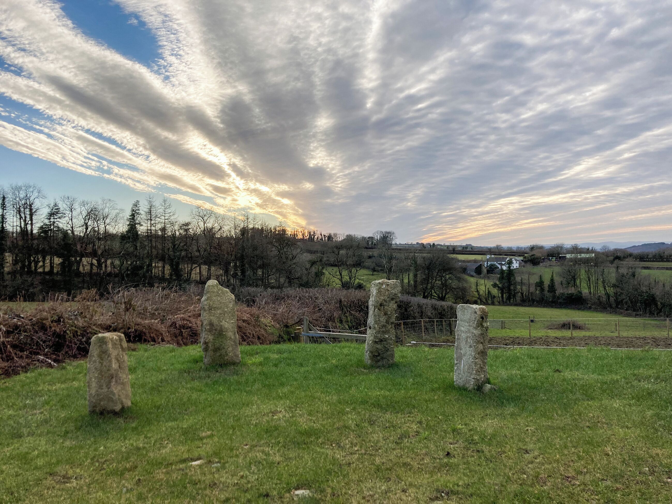 Ländliche Landschaft mit Steingebäuden, einem Zaun und einem Feld.