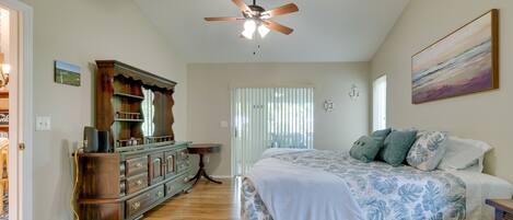 A bedroom with a bed, a ceiling fan, a dresser, and a window with blinds.